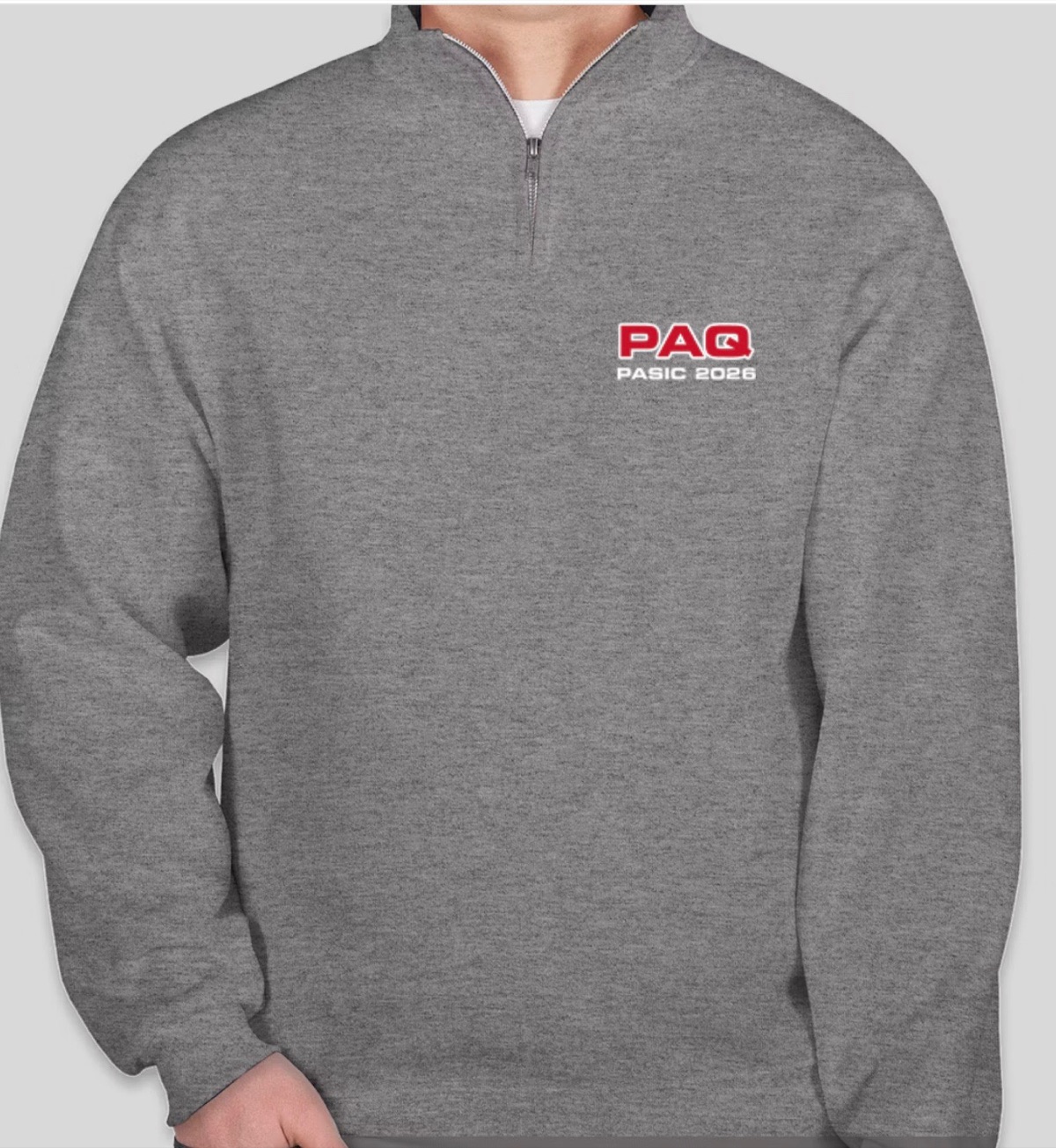 The new PAQ quarter-zip in Oxford grey, with a red PAQ logo and the words PASIC 2026 in white on the left chest.